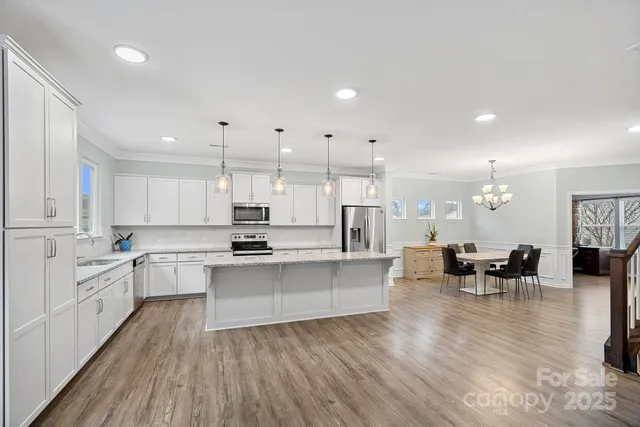 a large white kitchen with lots of counter top space and furniture