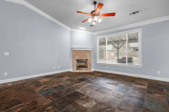 a view of an empty room with window and chandelier fan