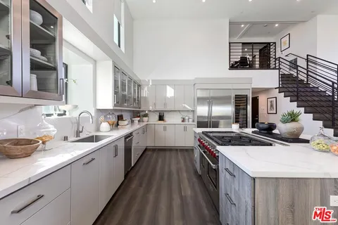 a kitchen that has a lot of white cabinets and stainless steel appliances
