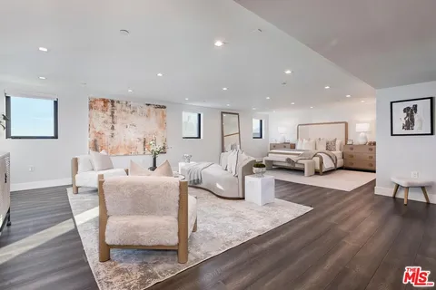 a spacious bedroom with a large bed and a painting on the wall