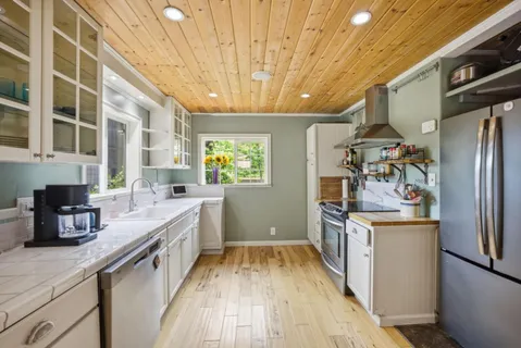 a kitchen with stainless steel appliances a stove a sink a refrigerator wooden floor and cabinets