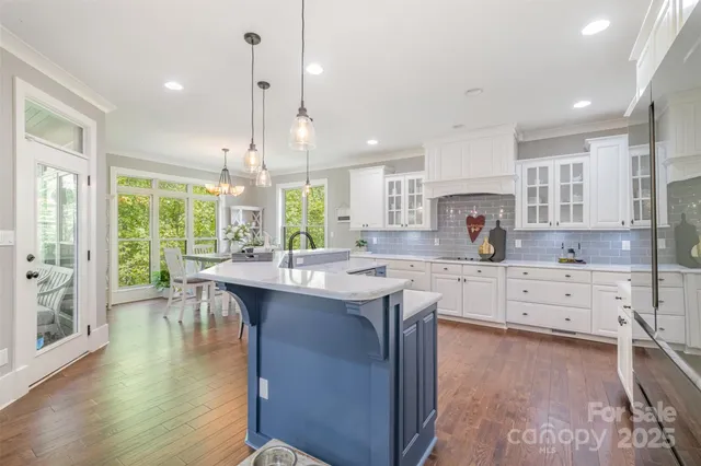 a kitchen with stainless steel appliances granite countertop a stove top oven a sink dishwasher a dining table and chairs with wooden floor