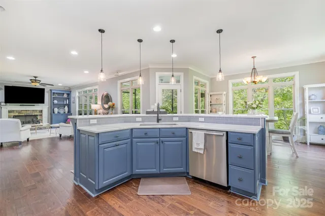a kitchen with stainless steel appliances granite countertop wooden floors and a view of living room