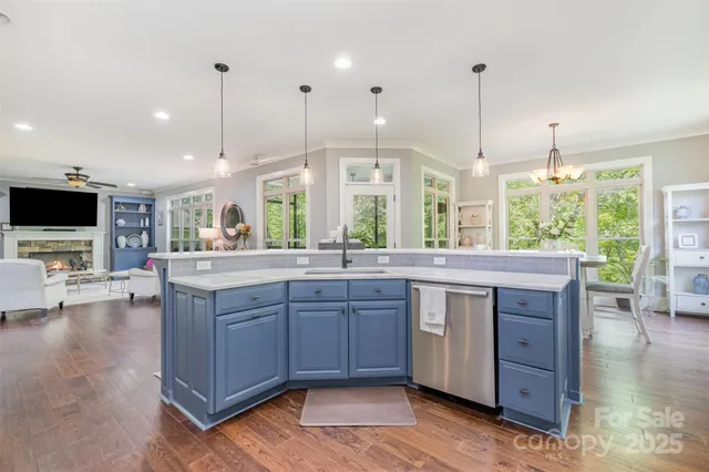 a kitchen with stainless steel appliances granite countertop wooden floors and a view of living room