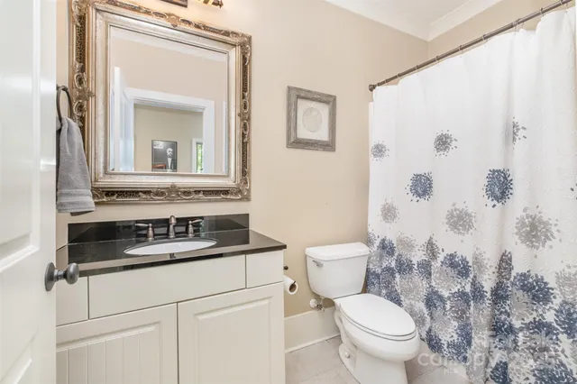 a bathroom with a granite countertop sink a toilet and a mirror