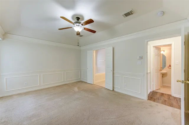 a view of an empty room and chandelier fan