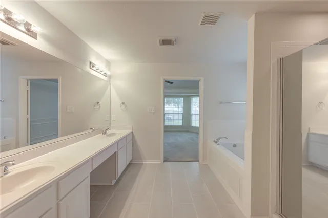 a spacious bathroom with a tub sink shower and mirror