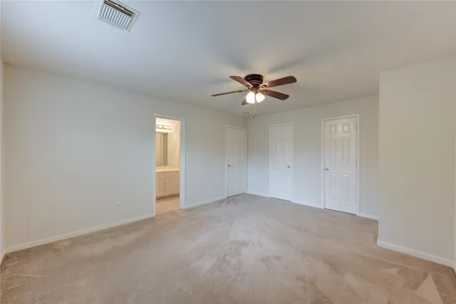 an empty room with a chandelier fan and wooden floor
