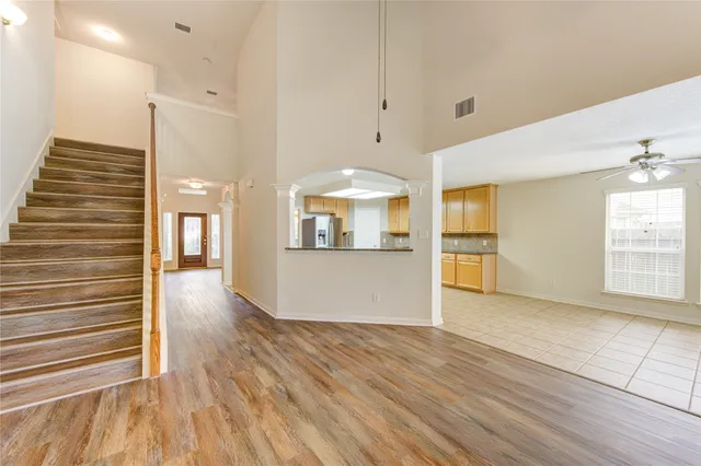 a view of a kitchen and an empty room with wooden floor