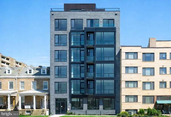 a front view of a building with glass windows and a yard