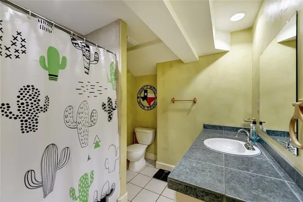 a bathroom with a granite countertop sink a toilet and shower