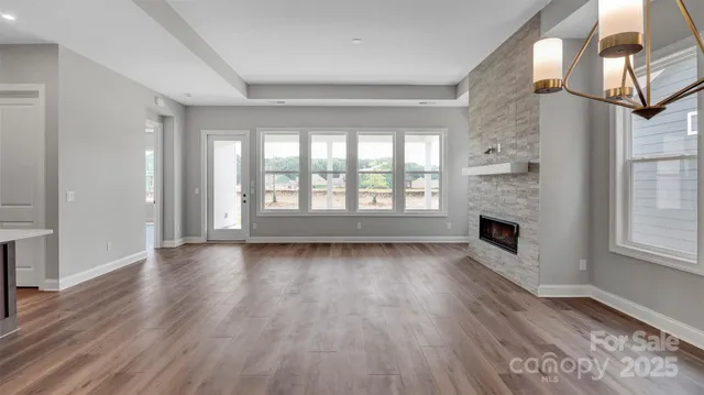 a large kitchen with stainless steel appliances a large counter top a stove a sink dishwasher and a fireplace with wooden floor