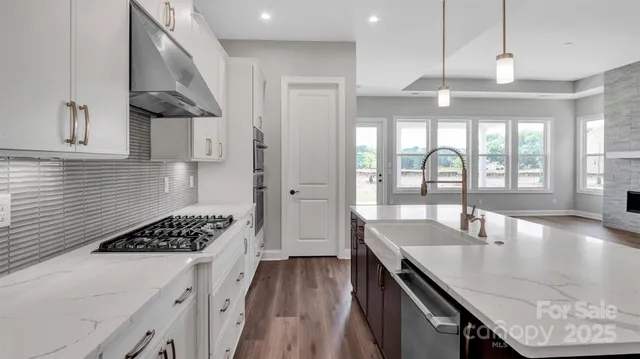 a kitchen with stainless steel appliances granite countertop a stove a refrigerator a sink a dining table and chairs with wooden floor