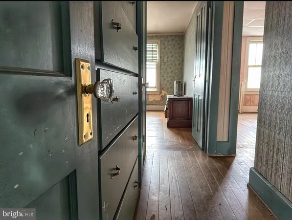 a view of a refrigerator in kitchen and an empty room