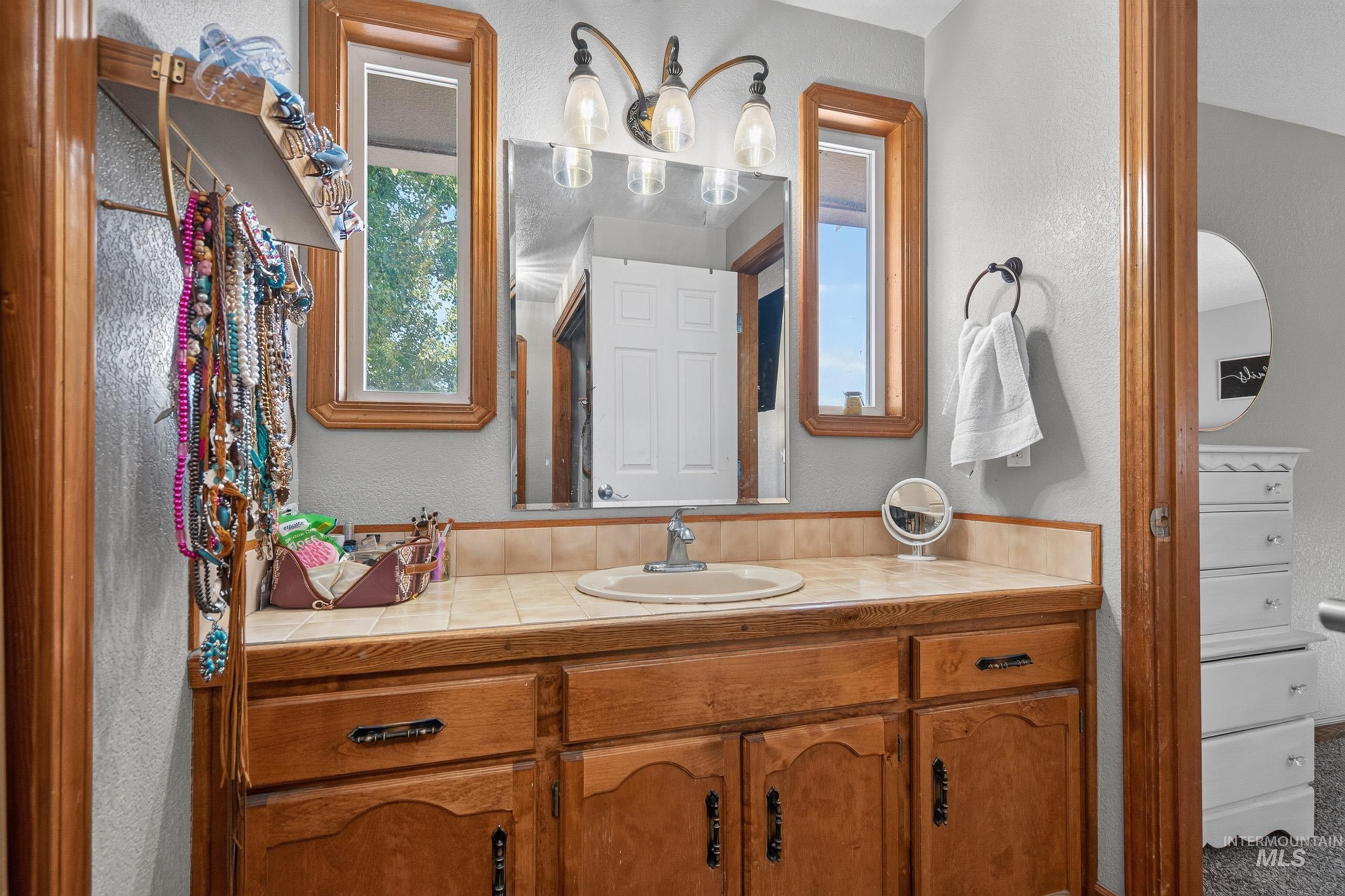 9696 Gloria Road Middleton, ID 83644 - Photo 18 of 50 Bathroom vanity featuring a tile countertop, integrated sink, and wood cabinetry with dark hardware