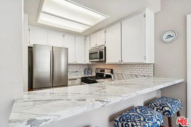 a kitchen with stainless steel appliances granite countertop a refrigerator a stove and a sink