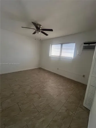 an empty room with windows and fan