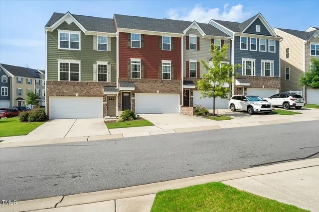 a front view of a residential apartment building with a yard and potted plants