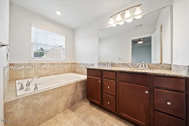 a spacious bathroom with a granite countertop tub sink and mirror