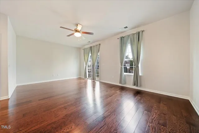 a view of an empty room with window and wooden floor