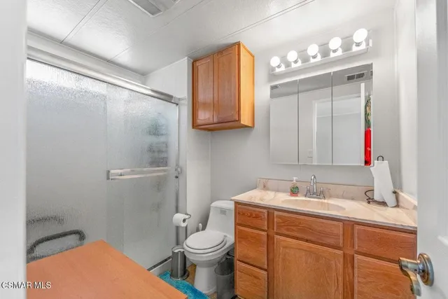 a bathroom with a sink vanity granite toilet and a mirror