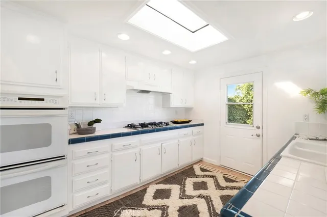 a kitchen with granite countertop white cabinets and white appliances
