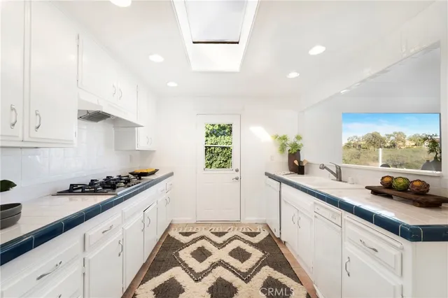 a kitchen with stainless steel appliances a sink a stove and white cabinets