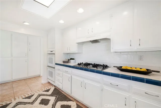 a kitchen with stainless steel appliances granite countertop a sink a stove and white cabinets
