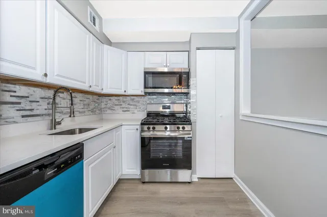 a kitchen with cabinets stainless steel appliances and a sink