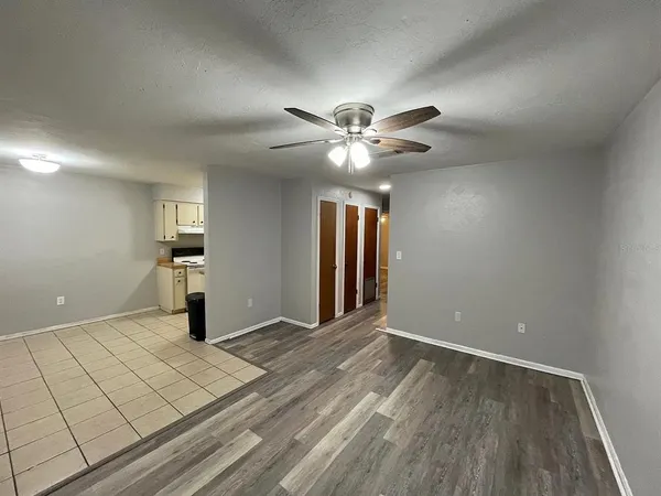 a view of an empty room with window and chandelier fan