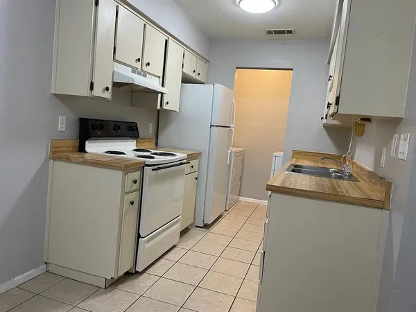 a kitchen with granite countertop a sink stove and refrigerator
