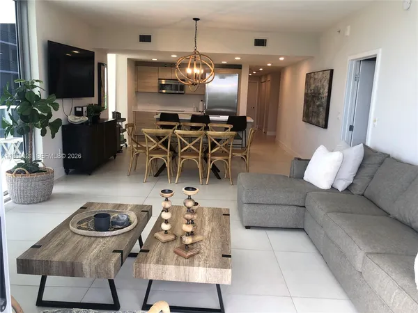 a living room with furniture a flat screen tv and kitchen view