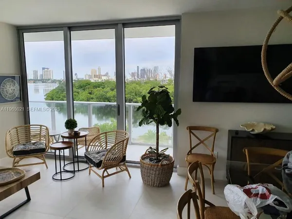 a living room with furniture a flat screen tv and a floor to ceiling window