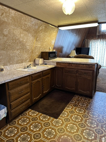 1085 West Elk Road Helper, UT 84526 - Photo 11 of 40 U-shaped kitchen area featuring wood cabinetry, white countertop, and a double basin sink