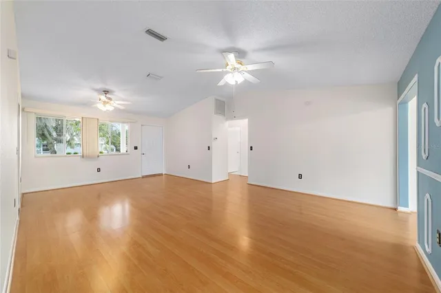 a view of an empty room with window and wooden floor