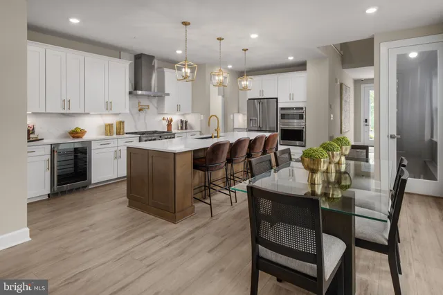 a kitchen with stainless steel appliances kitchen island granite countertop a table chairs sink refrigerator and cabinets