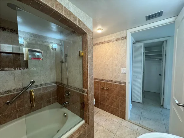a view of a hallway with wooden floor and a bathroom