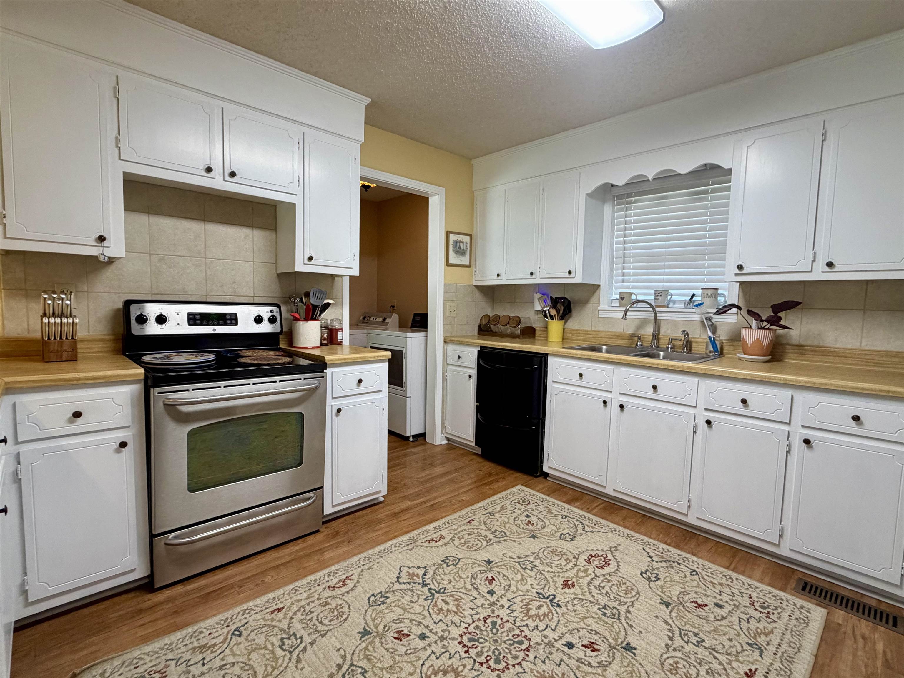 142 Treece Street Selmer, TN 38375 - Photo 8 of 36 Kitchen featuring white cabinetry, stainless steel range, black dishwasher, and wood-finish flooring