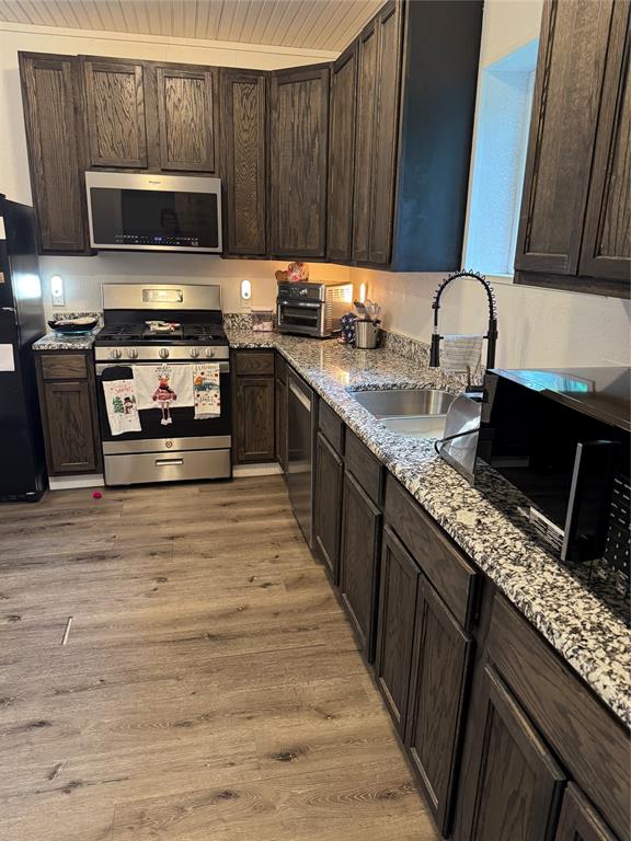 2300 Lyle Avenue Waco, TX 76708 - Photo 12 of 23 Kitchen featuring dark wood finish cabinets, black appliances, light stone countertops, light wood-type flooring, and wooden ceiling