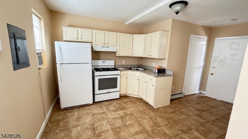 321 John Street Harrison, NJ 07029 - Photo 5 of 13 a kitchen with white cabinets and white appliances
