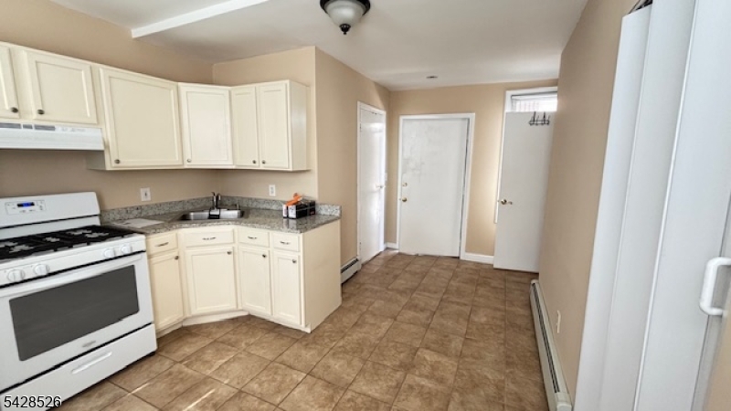 321 John Street Harrison, NJ 07029 - Photo 6 of 13 a kitchen with white cabinets and white appliances