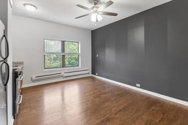 an empty room with wooden floor fan and windows