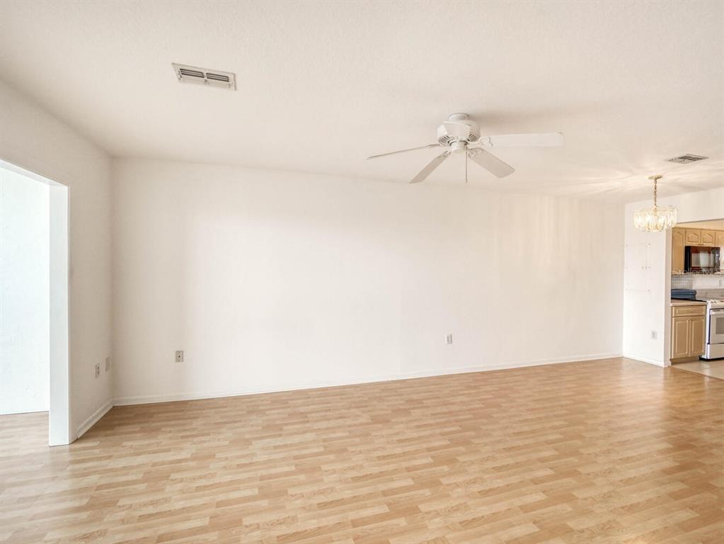 4939 Floramar Terrace, Unit 912 New Port Richey, FL 34652 - Photo 16 of 55 a view of an empty room with wooden floor and a ceiling fan