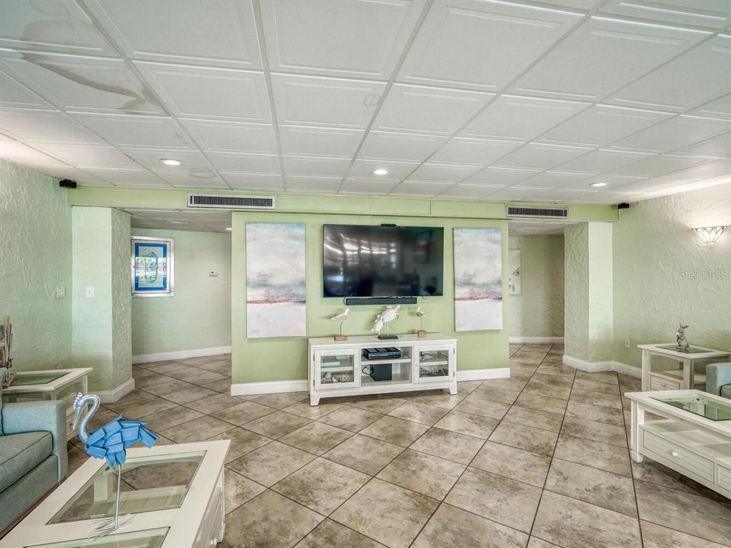 4939 Floramar Terrace, Unit 912 New Port Richey, FL 34652 - Photo 36 of 55 a view of a livingroom with furniture a flat screen tv and floor to ceiling window