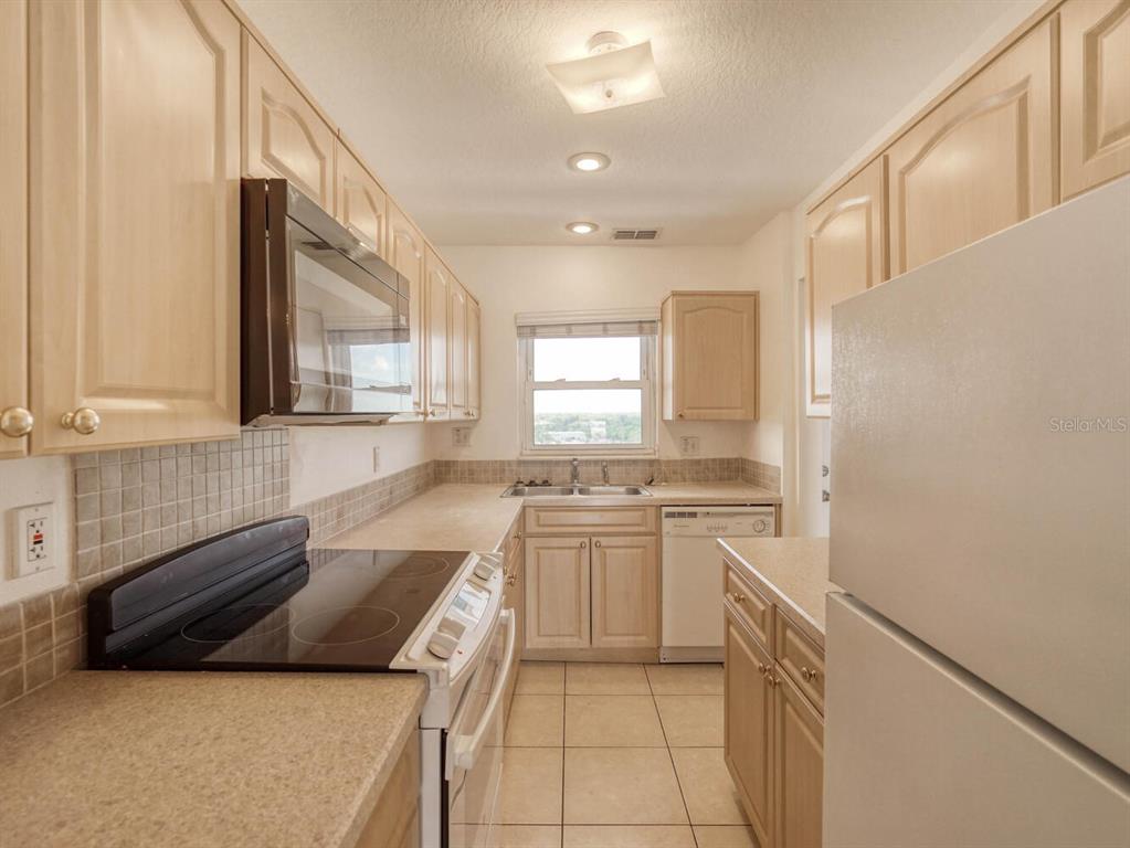 4939 Floramar Terrace, Unit 912 New Port Richey, FL 34652 - Photo 9 of 55 a kitchen with a stove a sink and a refrigerator