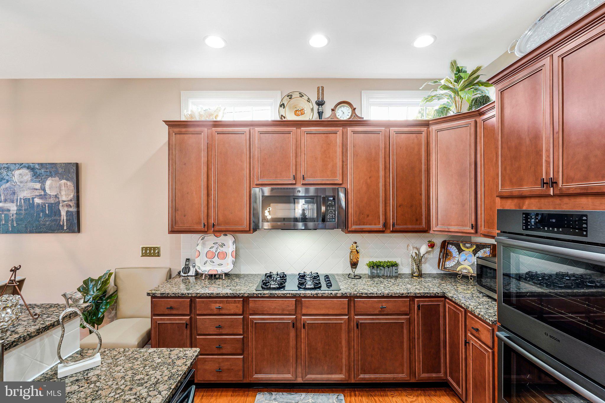 15517 Legacy Way Haymarket, VA 20169 - Photo 10 of 68 a kitchen with granite countertop wooden cabinets a sink a stove and a window
