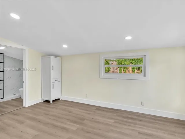 an empty room with wooden floor and window