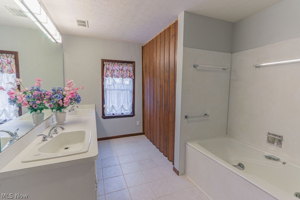 51883 Telegraph Road Amherst, OH 44001 - Photo 10 of 49 Bathroom featuring vanity, a textured ceiling, tile patterned floors, and a bath