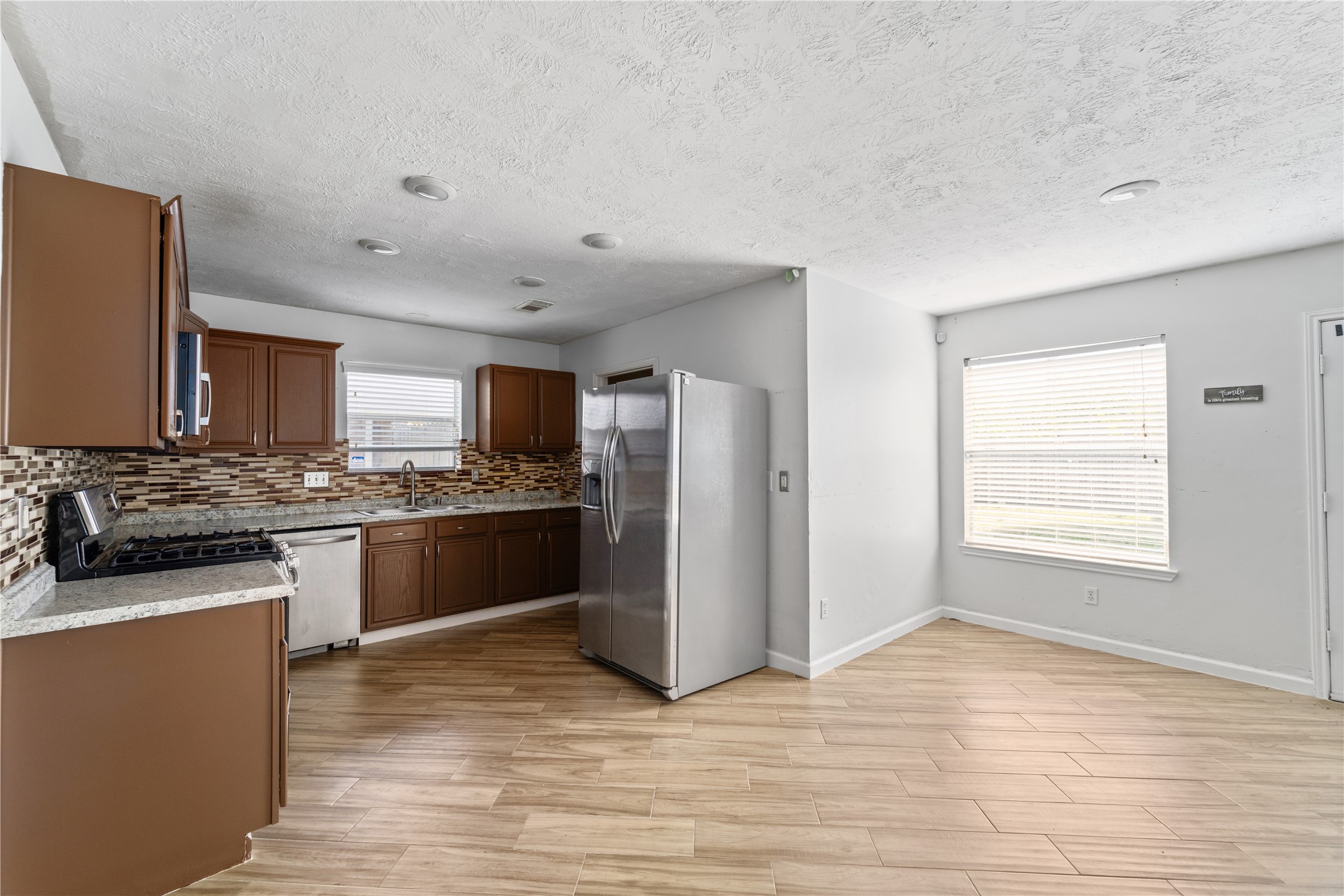 11959 Swords Creek Road Houston, TX 77067 - Photo 11 of 30 a kitchen with stainless steel appliances granite countertop a refrigerator a sink dishwasher a stove with wooden cabinets and floor