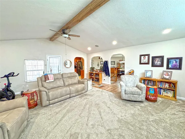 a living room with furniture kitchen view and a large window